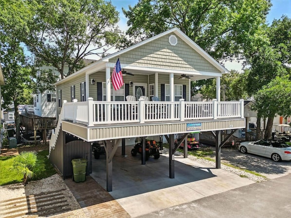 A single-story house with a porch, an American flag, and a sign that reads 'Buch Haven.'