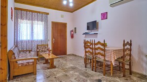 A cozy room with a wooden ceiling, a sofa, a table, and chairs. - Theodora Apartment 1 Agios Stefanos Corfu (Corfu)