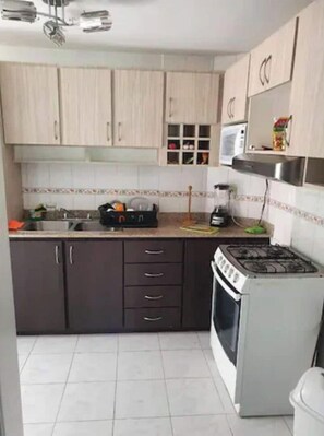 A kitchen with light wooden cabinets, a gas stove, a microwave, and a sink. - Quiet and cozy apartment: 2 bedrooms 2 bathrooms and balcony.  (Panamá)