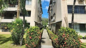A pathway flanked by buildings with balconies and palm trees.