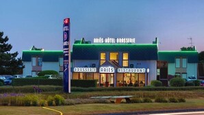Un hôtel doté d’un toit végétalisé et d’une enseigne indiquant « Aries Hotel Brasserie » et « Aries Restaurant ».