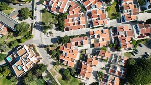 Vue aérienne d’un quartier résidentiel avec des maisons à étages, une piscine et un parking.