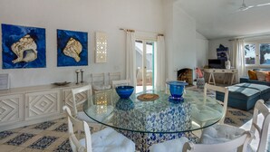 Un coin repas avec une table en verre, des chaises blanches et des bols décoratifs bleus.