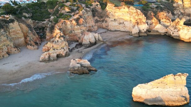 Un paysage côtier caractérisé par des formations rocheuses et une mer d’un bleu limpide.