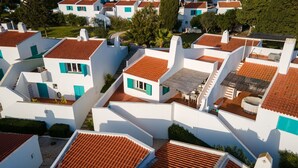 Un quartier résidentiel caractérisé par des bâtiments blancs et des toits recouverts de tuiles rouges, agrémenté de balcons et d’espaces aménagés pour se détendre en plein air.
