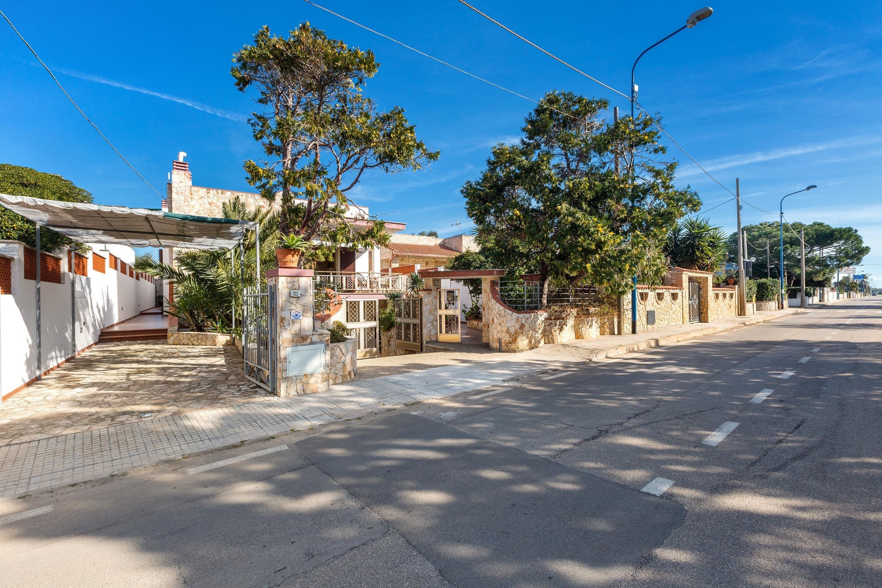 A street view with a row of houses, a paved sidewalk, and a clear blue sky.