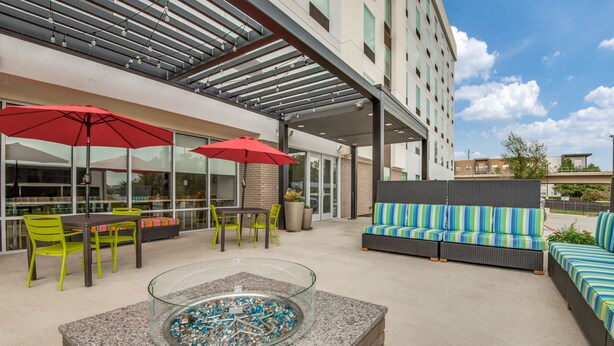 An outdoor patio area with a fire pit, seating, and umbrellas.