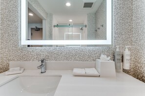 Ein modernes Badezimmer mit einem großen Spiegel, einem Waschbecken und zwei Handtuchhaltern.