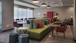 A modern lounge area with a green sofa, round tables, and chairs.