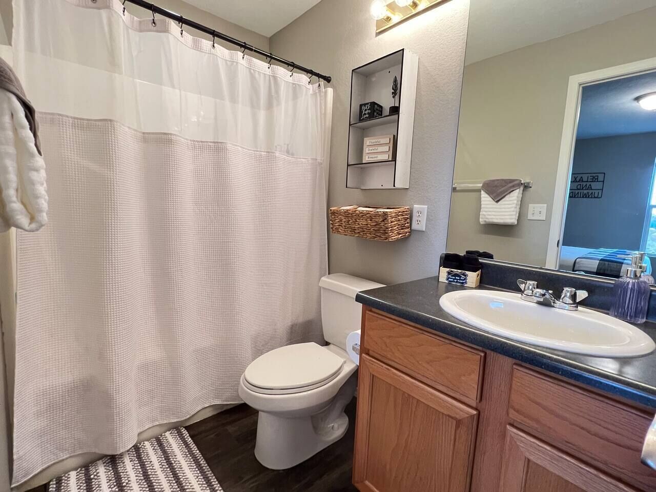 A bathroom with a white toilet, a wooden vanity with a sink, and a shower curtain.