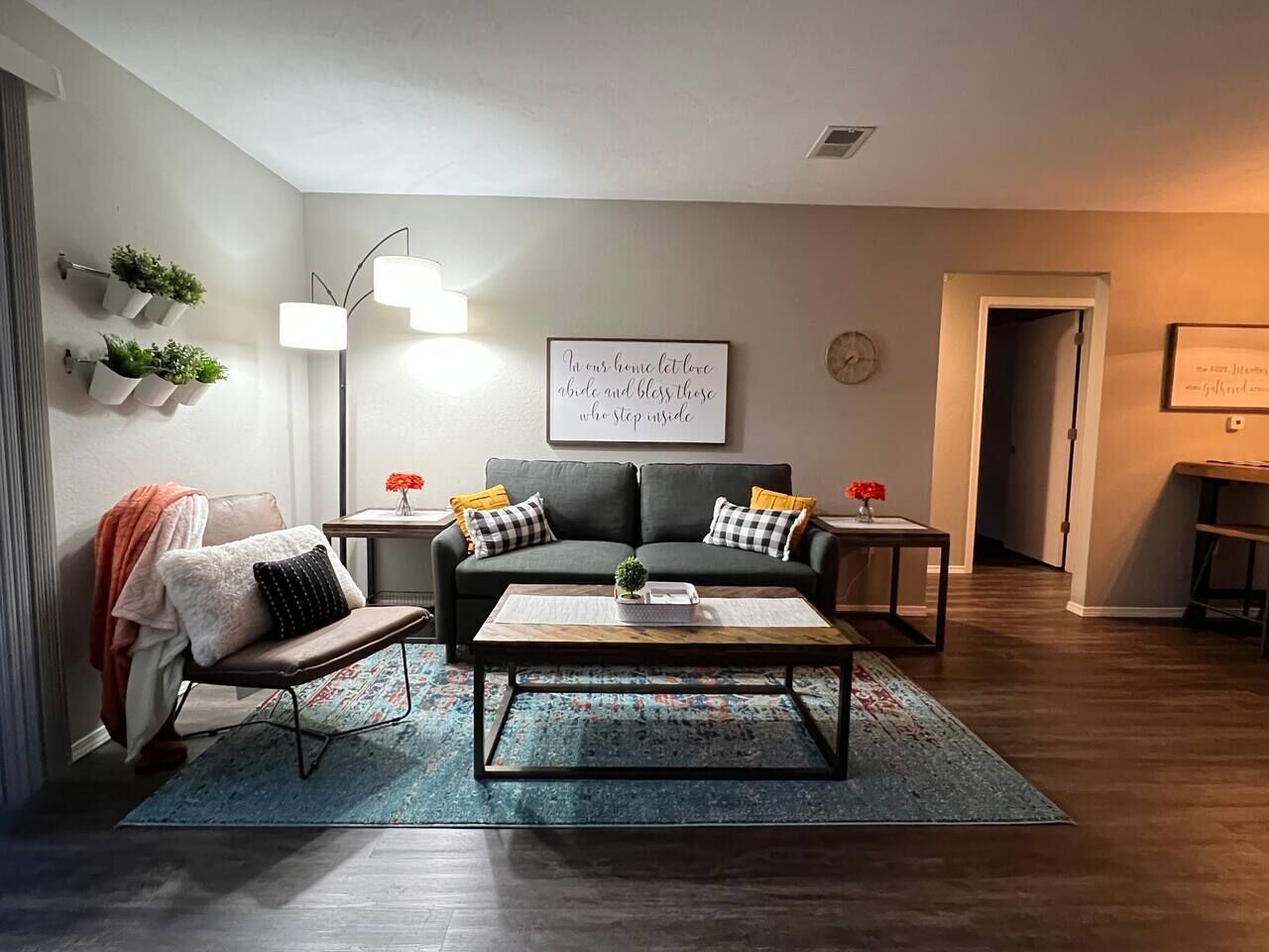 Ein Wohnzimmer mit einer Couch, einem Sessel, einem Couchtisch und einer Wandleuchte.