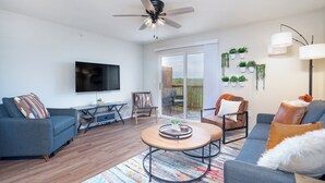 Un salon moderne doté d’un téléviseur à écran plat, de deux canapés, d’une table basse et d’un ventilateur de plafond.