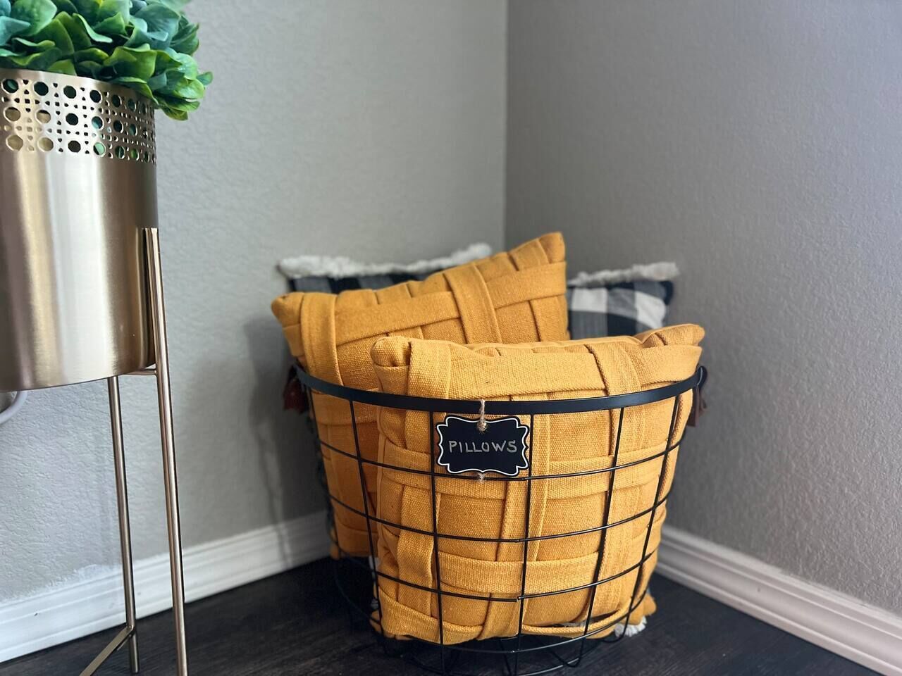A corner with a wire basket labeled 'PILLOWS' containing several yellow pillows.