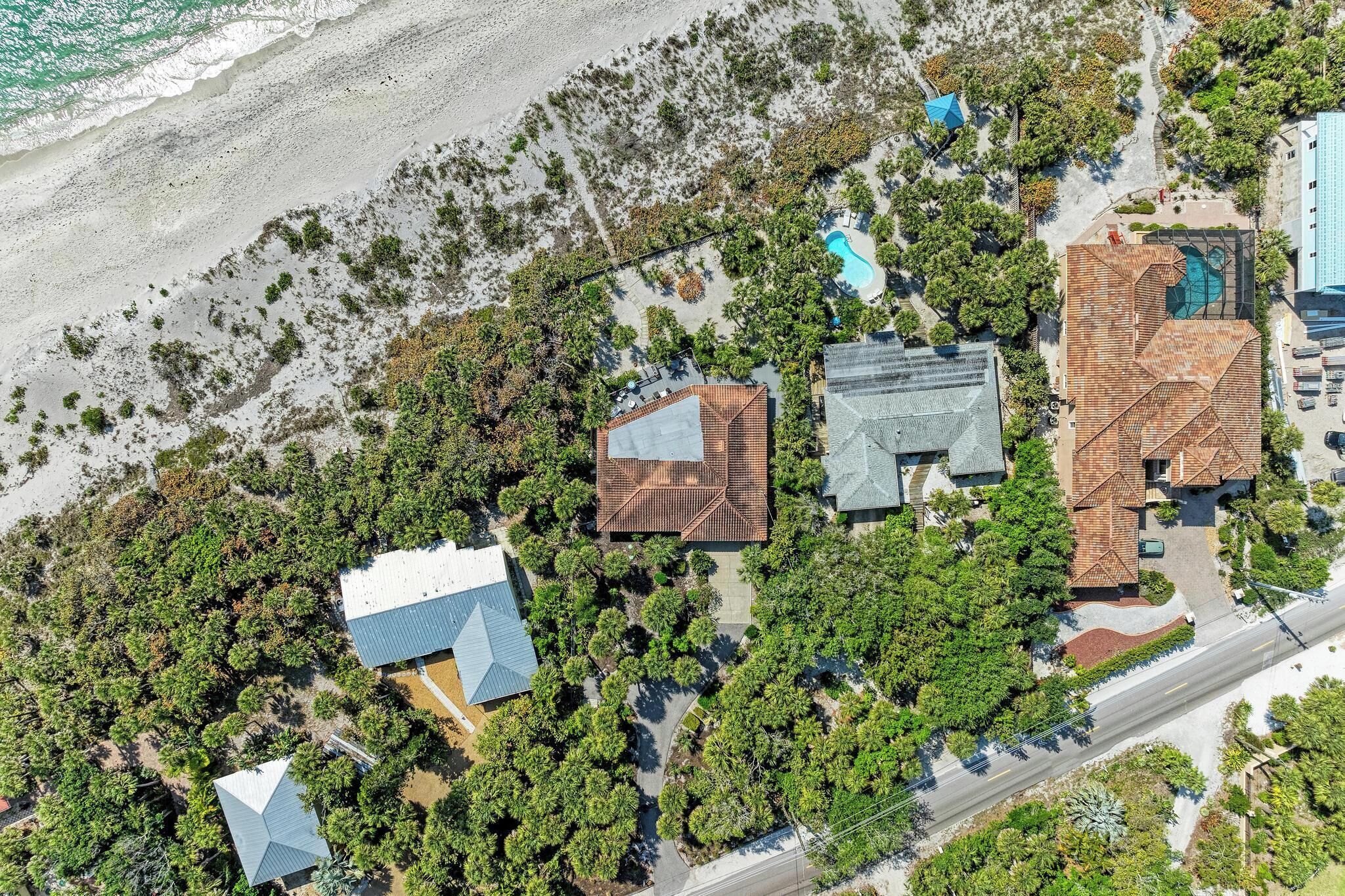 Ein Luftbild einer Küstenimmobilie mit mehreren Gebäuden, einem Swimmingpool und einem Strand.