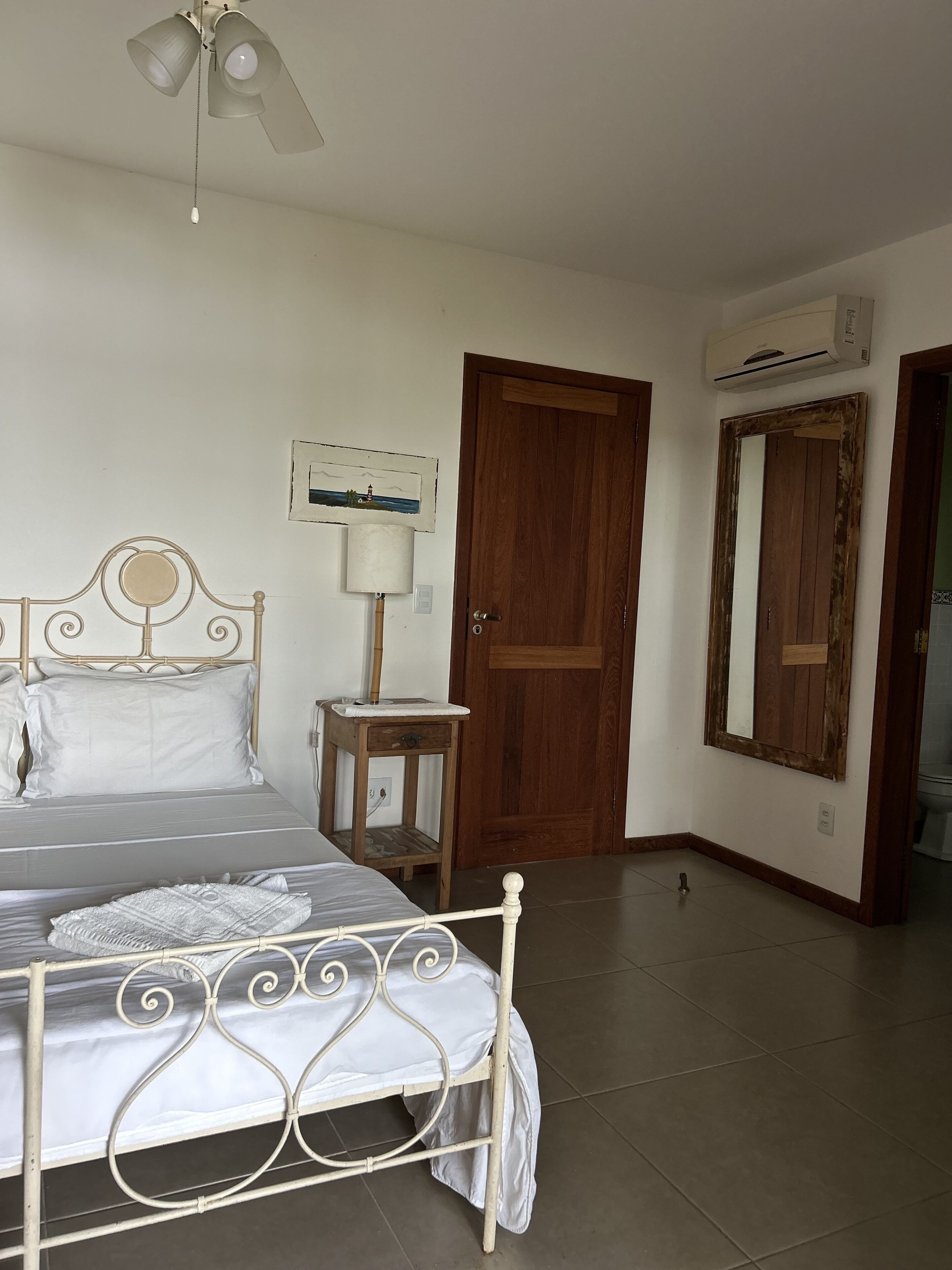 Un dormitorio con cama, mesita de noche, lámpara y ventilador de techo.
