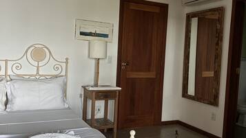 Un dormitorio con cama, mesita de noche, lámpara y ventilador de techo.