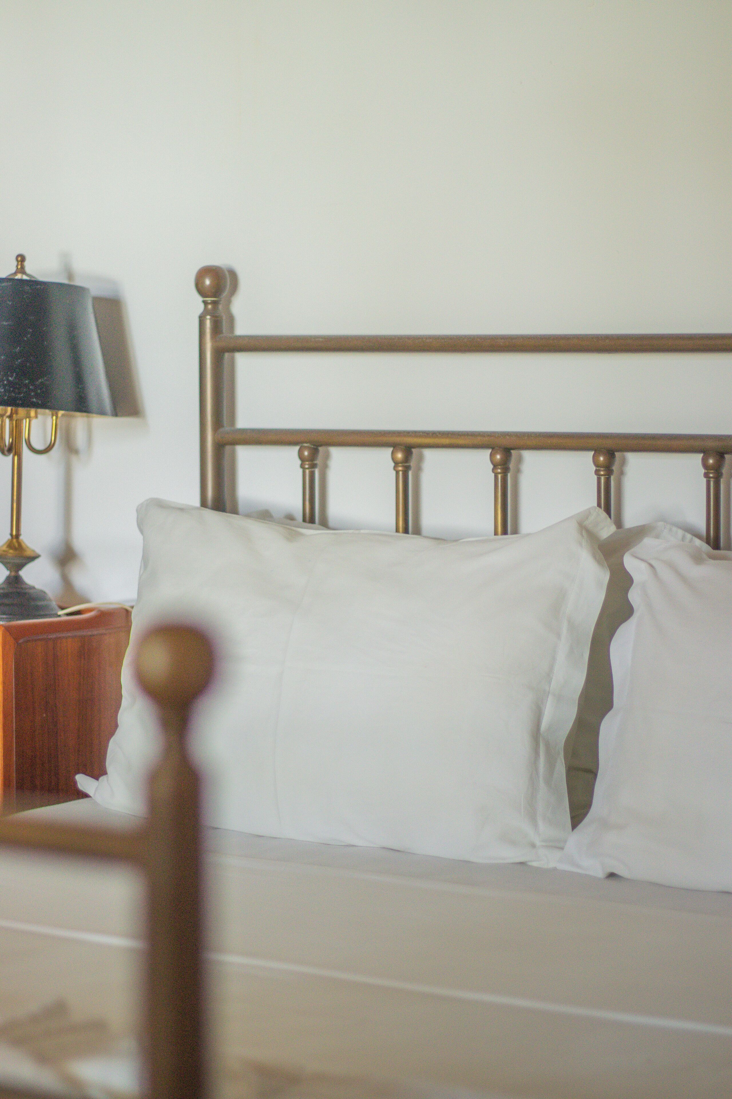 Un lit avec une tête de lit en bois et du linge de lit blanc.