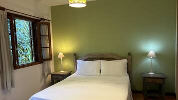 A neatly made bed with white linens, a wooden headboard, and two bedside lamps.