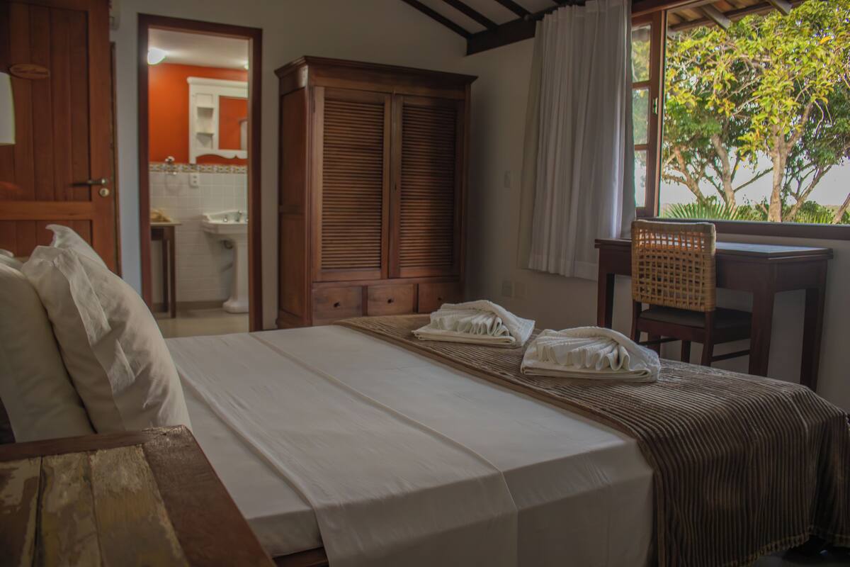 Un dormitorio con una cama, un armario de madera, un escritorio y una silla.