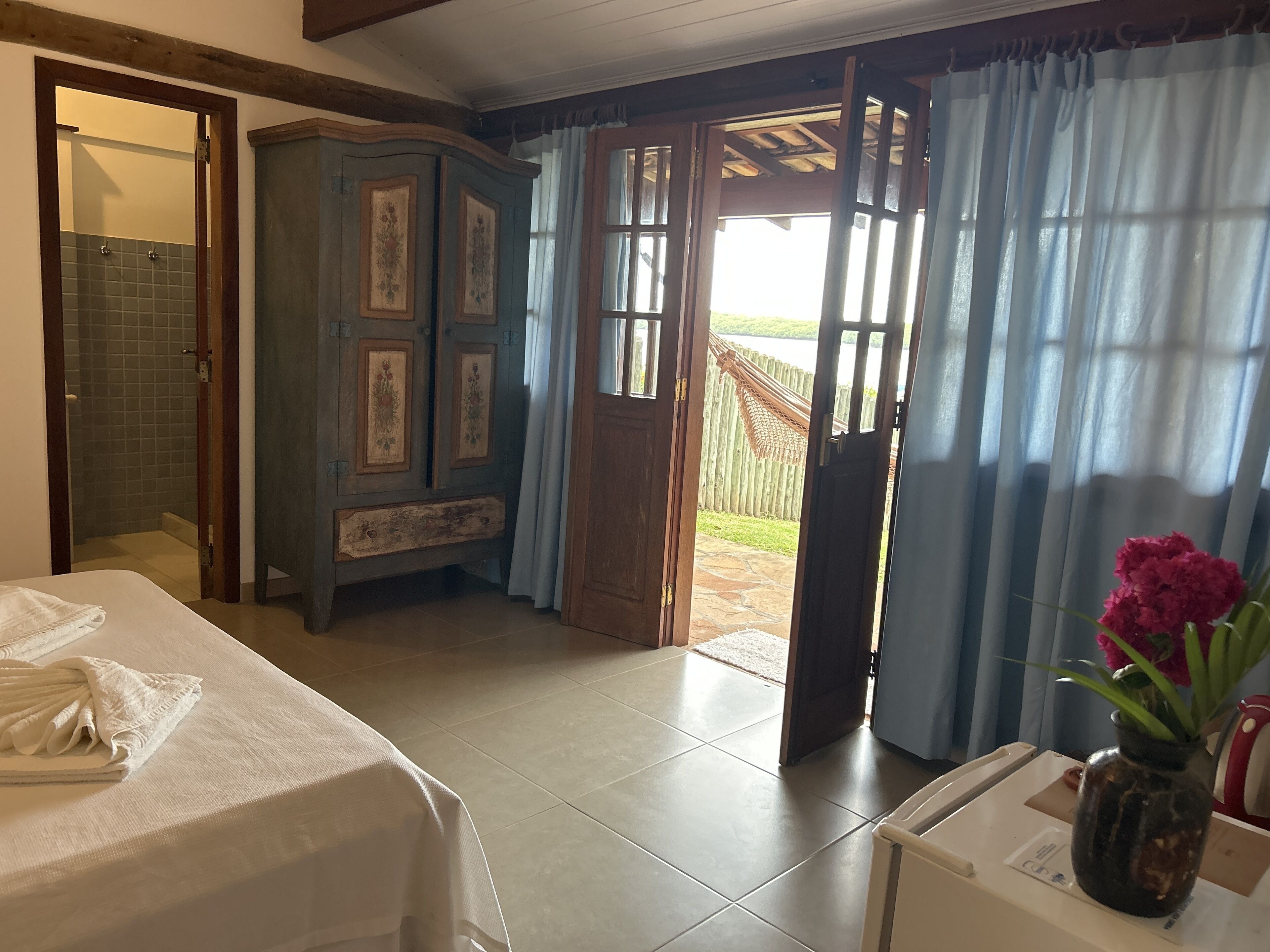 Una habitación con una cama, un armario de madera y una puerta que da a un espacio exterior.
