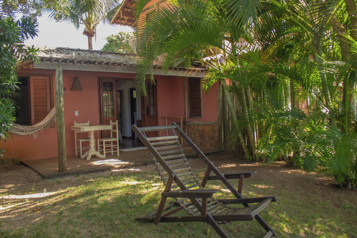Una pequeña casa con terraza de madera, una hamaca y una silla de descanso.