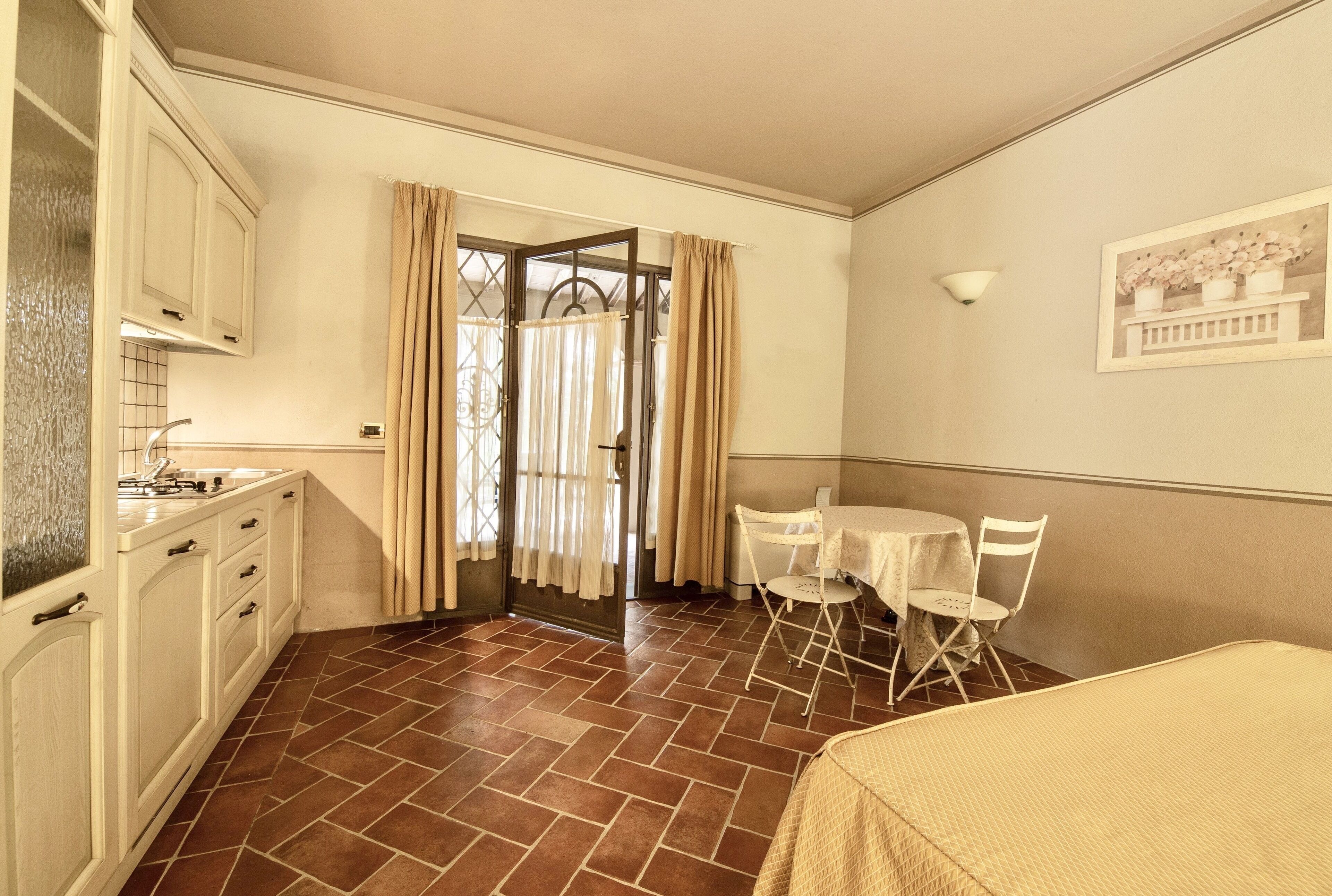 Una habitación compacta con kitchenette, una zona de comedor con mesa y sillas, y una cama.