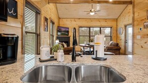 A kitchen with granite countertops, a double sink, and a ceiling fan. - New Build! Hot Tub, Fireplace (Pigeon Forge)
