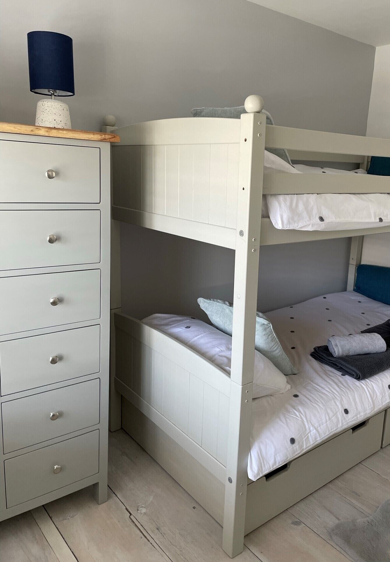 A bunk bed with a dresser and a lamp.