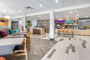 A modern hotel lobby with a reception desk, seating area, and a kitchenette. - Home2 Suites Lexington Keeneland Airport, KY (Lexington)