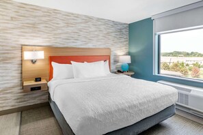 A hotel room with a bed, two bedside tables, a window with a view, and a wall with a textured pattern. - Home2 Suites Lexington Keeneland Airport, KY (Lexington)