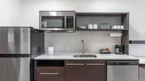 Eine moderne Küche mit Edelstahlkühlschrank, integriertem Mikrowellenherd, Geschirrspüler und Kaffeemaschine.