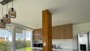 Una cocina moderna con armarios de madera, un refrigerador de acero inoxidable e iluminación colgante.