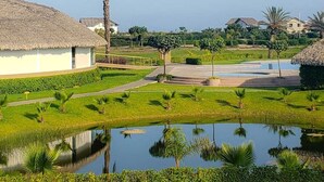 Un resort con edificios de techo de paja, una fuente central y céspedes bien cuidados.