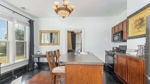 A kitchen with a large island, wooden cabinets, a chandelier, and a view of the outdoors. - Spacious 1bd, Close to Beach, Shops, Food & Mall (Michigan City)