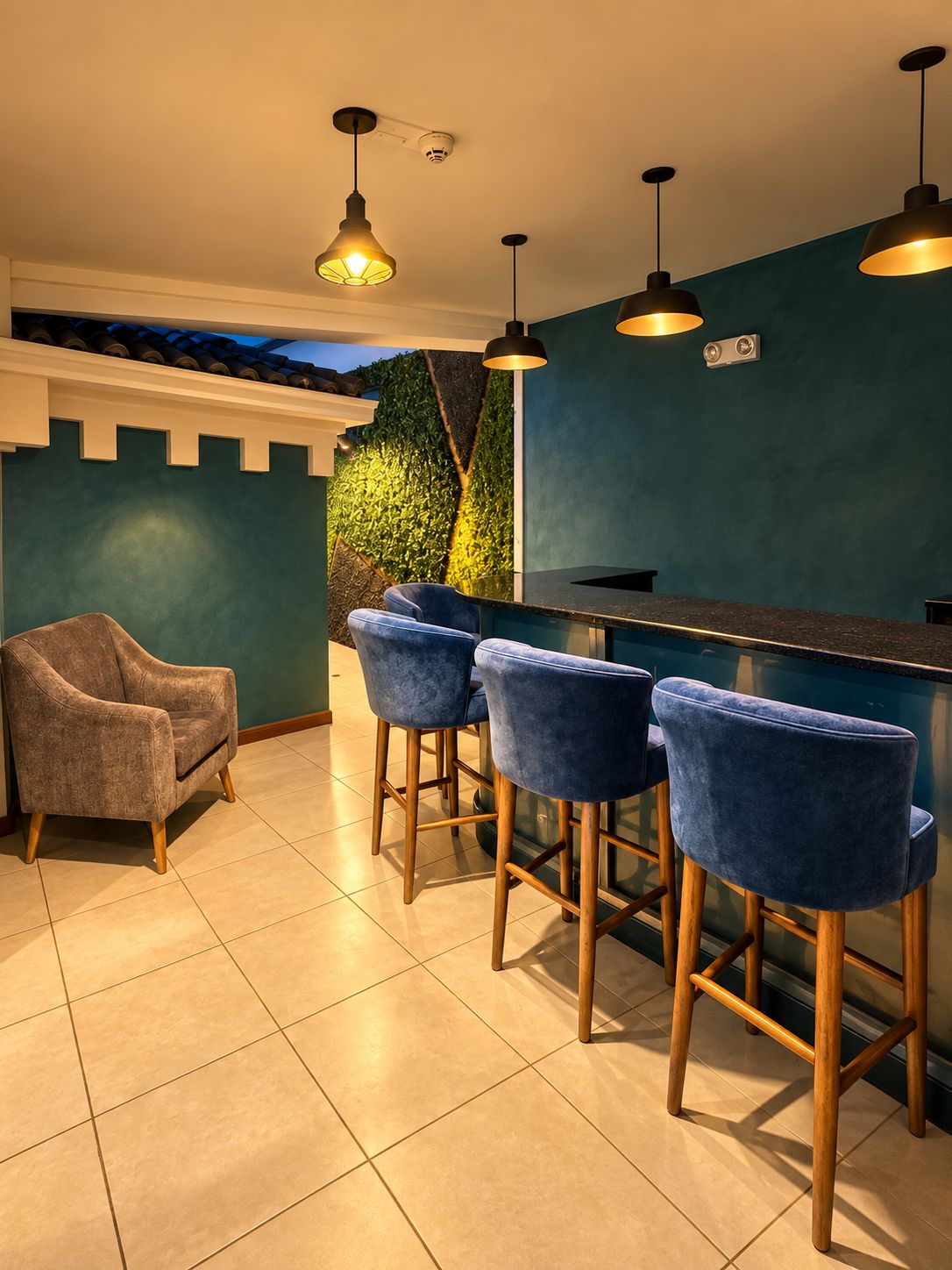 Un área de bar con pared verde, un sofá y taburetes.
