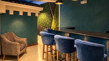 Un área de bar con pared verde, un sofá y taburetes.