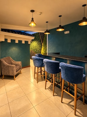 Un área de bar con pared verde, un sofá y taburetes.