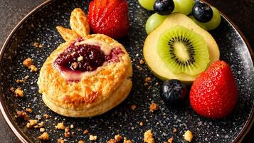 Une assiette de dessert avec une pâtisserie, des fraises, des kiwis et des raisins.