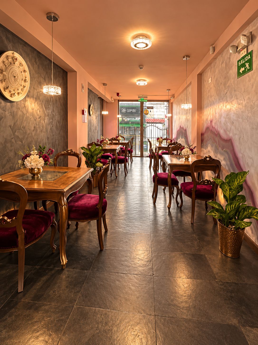 Een restaurantinterieur met houten tafels en stoelen, een marmeren wand en een groen vluchtbord.