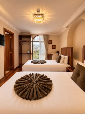 A hotel room with two beds, a television, a wardrobe, and a balcony with a view. - Dakani Hotel Boutique  (Quito)