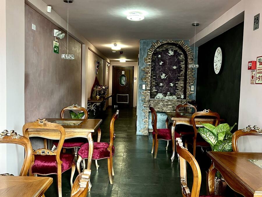 Ein Hotelgang mit Holztischen und -stühlen, einer Wand mit Teekannen und Notausgangsschildern.