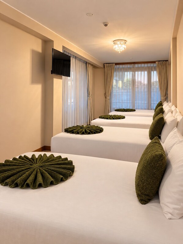Habitación de hotel con dos camas, un televisor de pantalla plana en la pared y un candelabro.