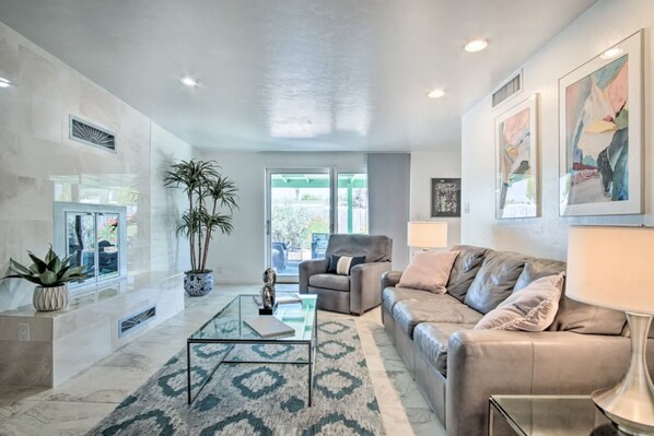 Relax in this stylish living room with a leather sofa, glass coffee table, and lush greenery.