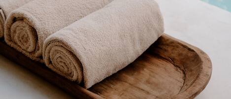 A wooden tray with rolled beige towels.