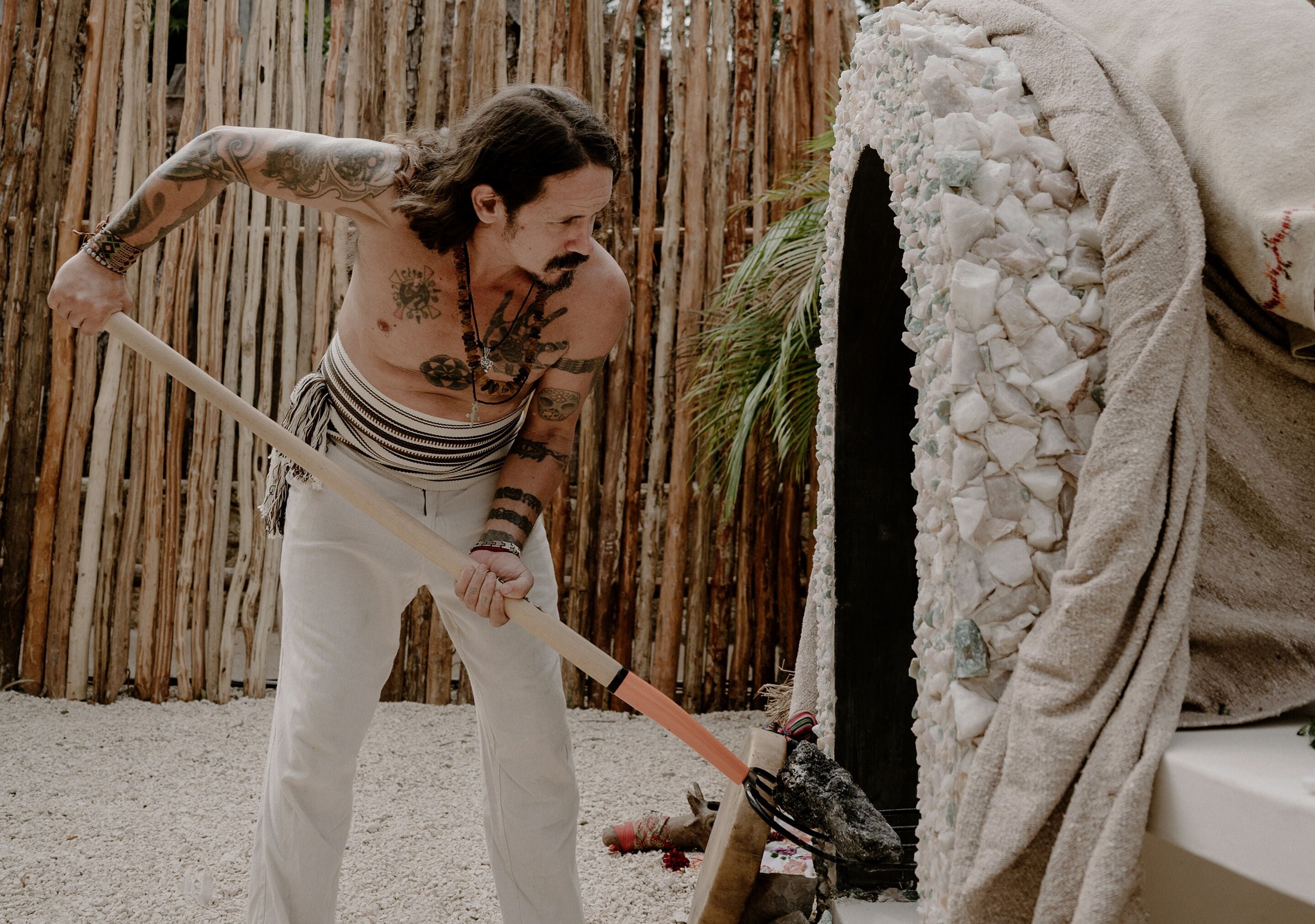 A person with tattoos holding a stick.