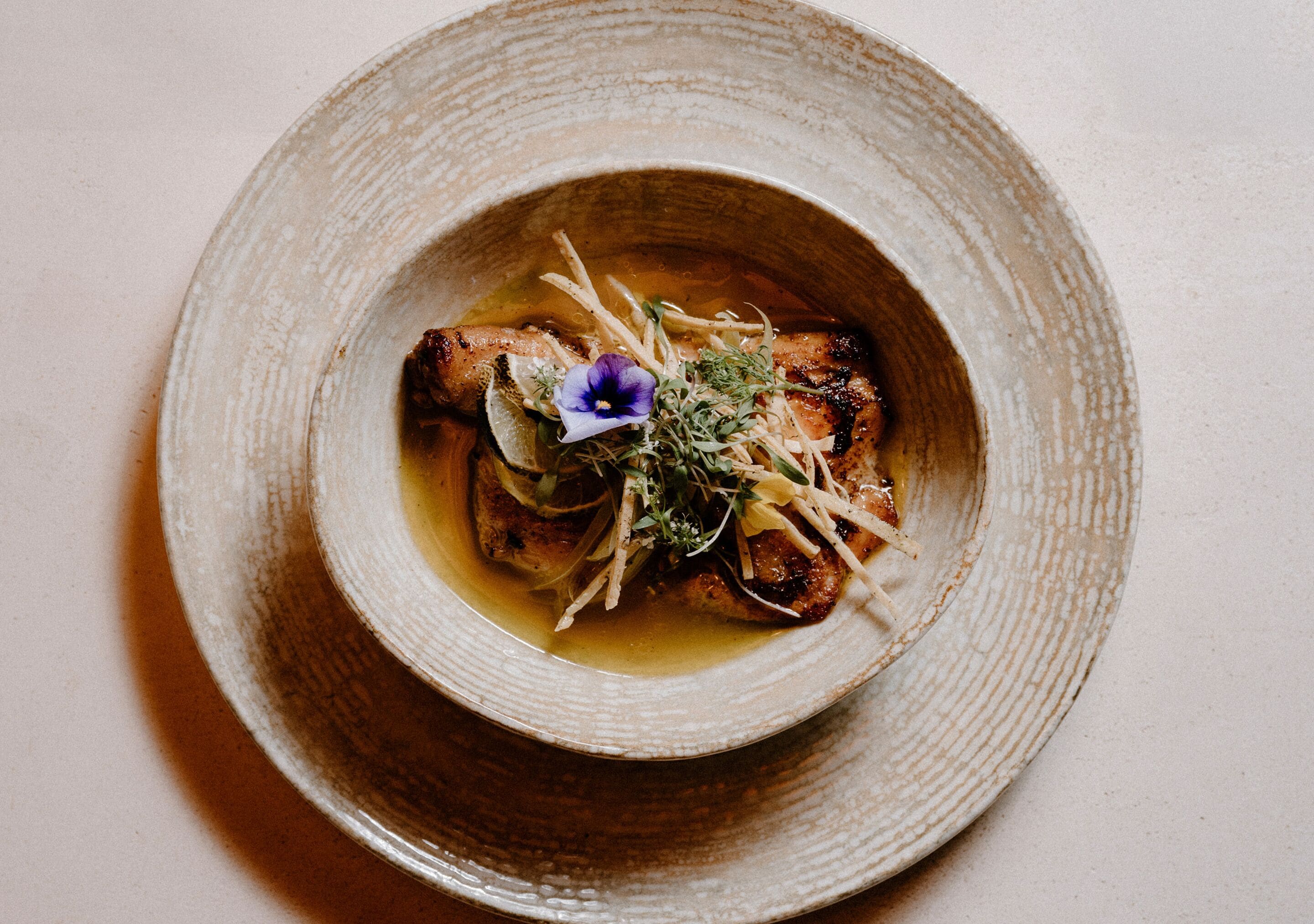 A dish with a flower garnish on a ceramic plate.
