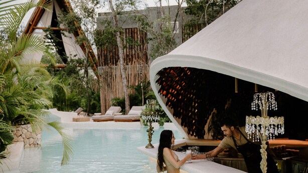 A poolside area with a bar, lounge chairs, and a covered seating area.