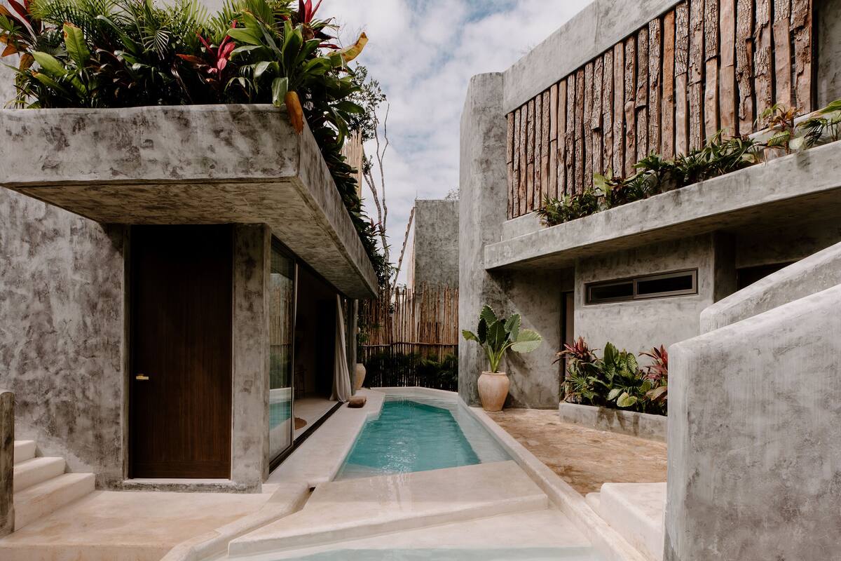 Un edificio moderno con piscina, arquitectura de concreto y abundante decoración de plantas.