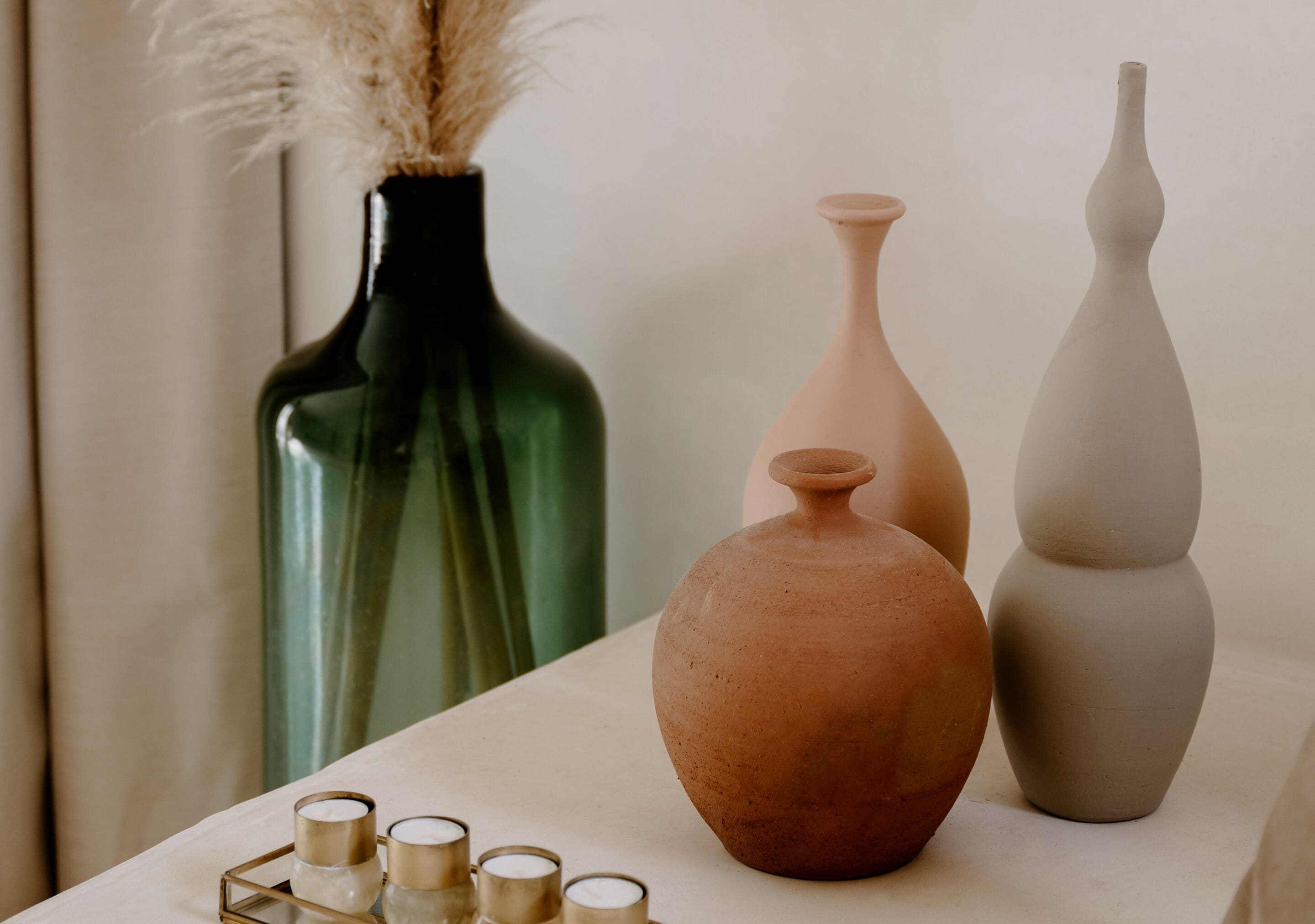 A table with three vases and a tray of candles.