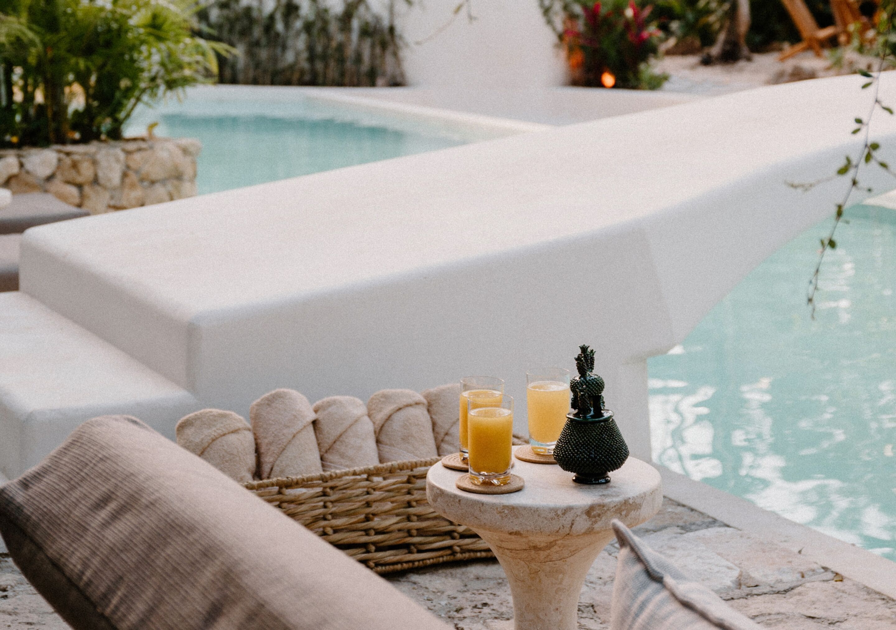 A poolside area with lounge chairs, a small table with drinks and bread, and a decorative figure.